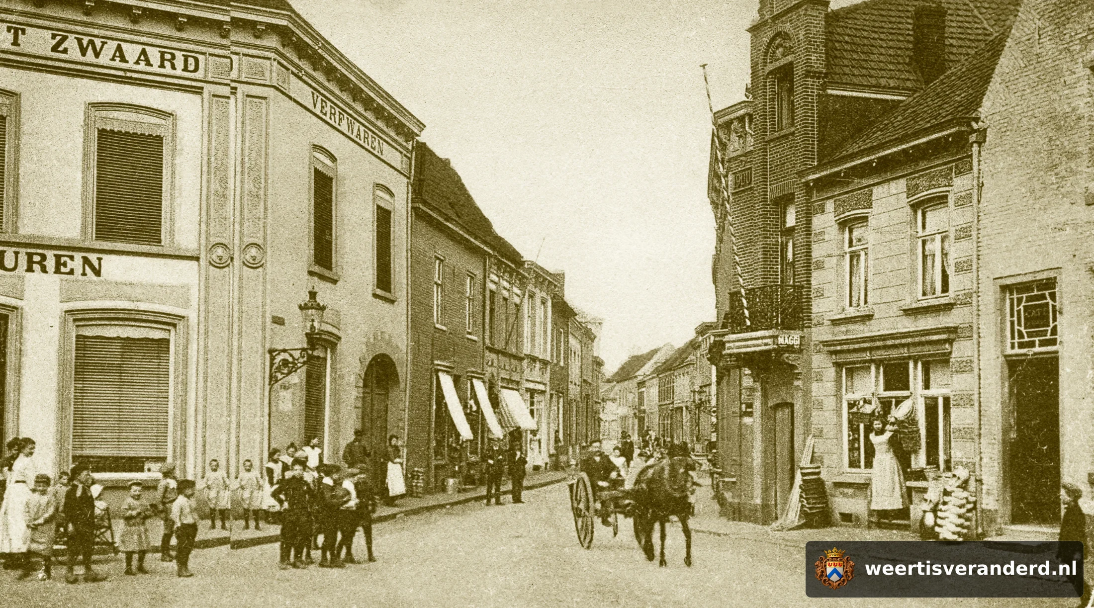 Hier heeft het pand van Koloniale Waren Het Zwaard nog een grote poort aan de zijde van de Hoog straat. Deze verdween bij de verbreding van het pand ernaast, waar later de ijszaak van Väös Janssen gevestigd was. In de winkel rechts met de d