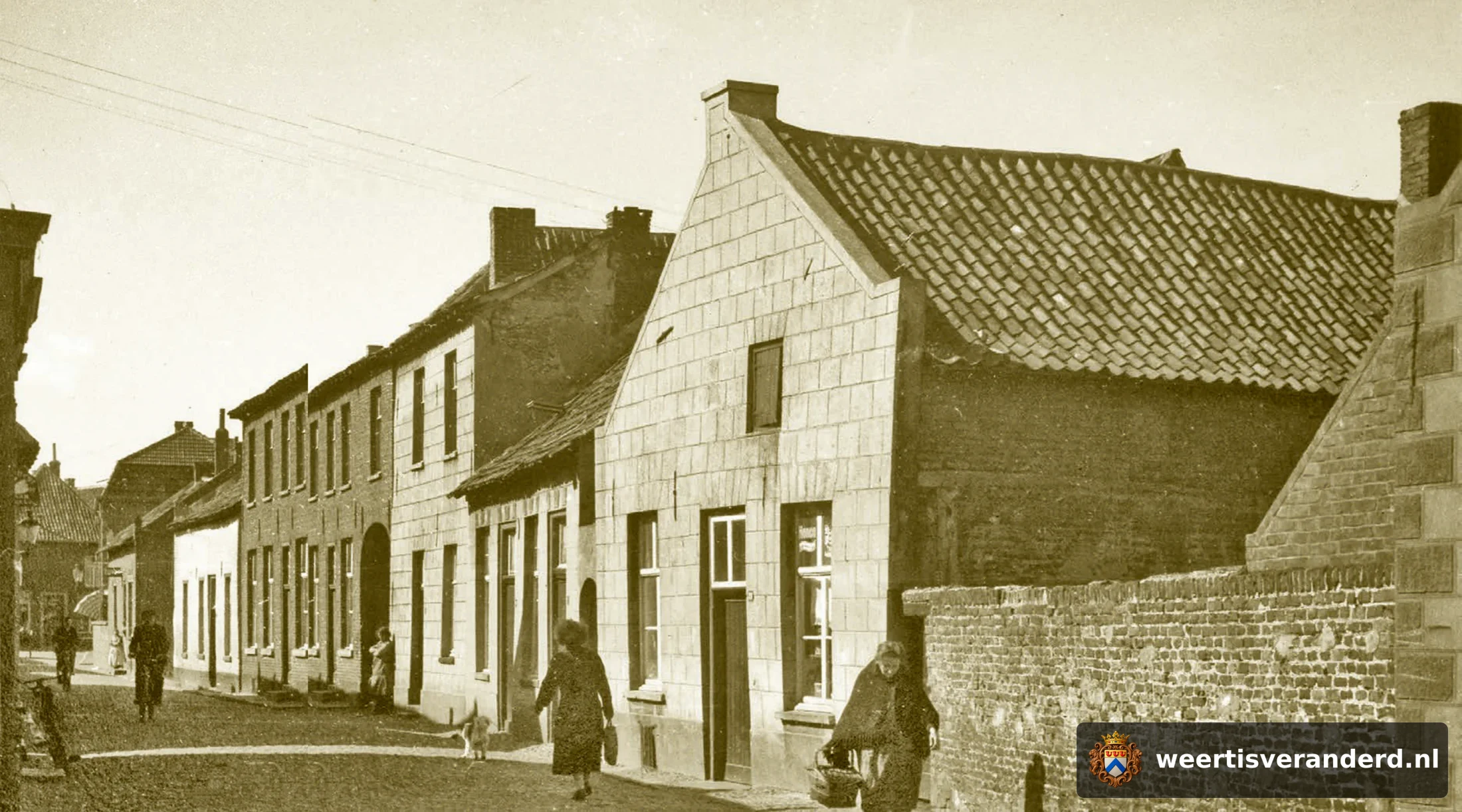 De Hogesteenweg gezien vanaf de Oelemarkt richting Beekstraat. Let op het vrouwtje op de voorgrond met körref en nuizik. In het witte pand vooraan woonde de familie Claessens (van Potten Ties), daarnaast Adriaens (van Baks). In het kleine h