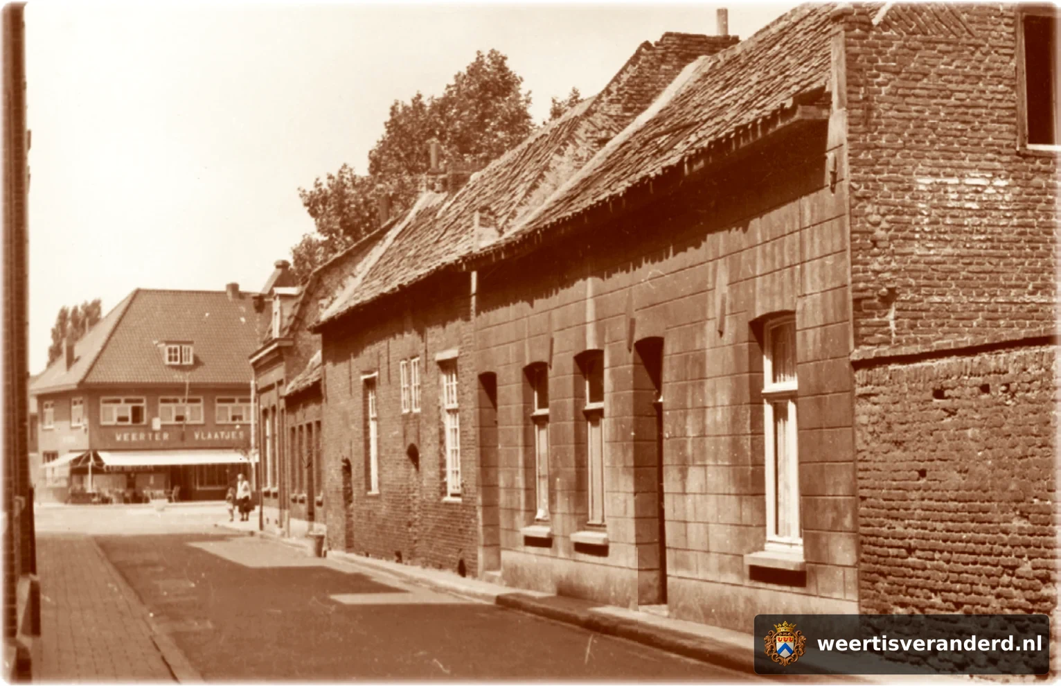 De lage huisjes aan het einde van de straat waren gebouwd als hofje in de zeventiende eeuw door de familie Ververs. In het huis op de hoek woonde vroeger de molenaar van de Binnenmolen, die er vlakbij stond. Op de achtergrond zien we de voo