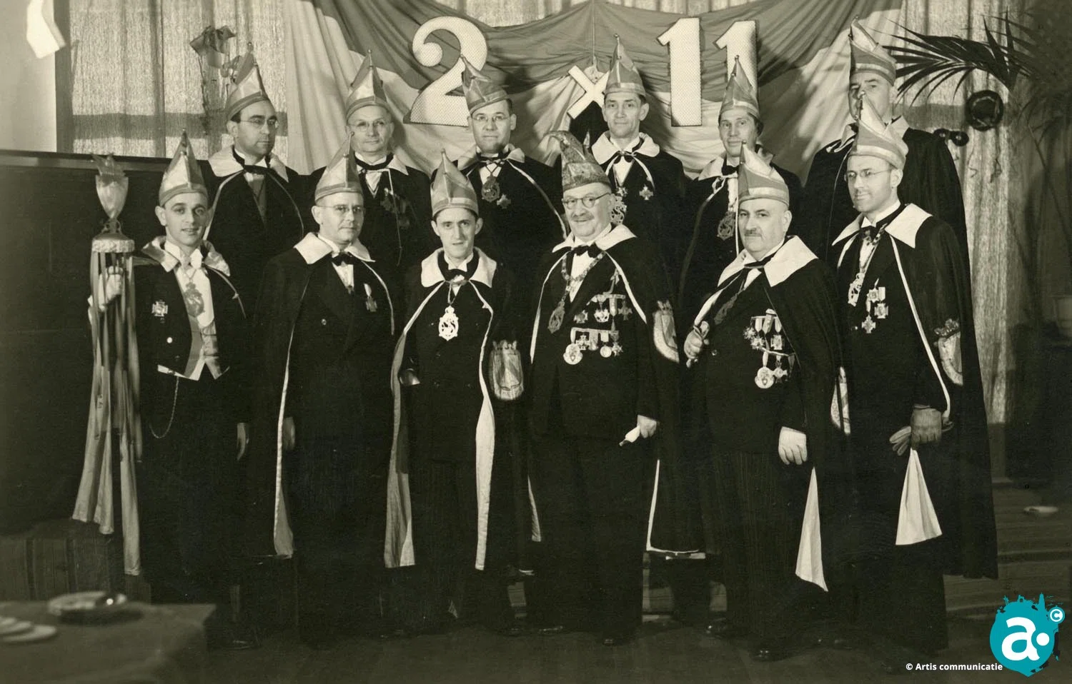 Raad van Elf. Achterste rij v.l.n.r.: Giel Meewis, Sjang Vincken, Jan Nouwen, Jan Grein, Pierre Grein en Harrie Kimmel. 
Voorste rij v.l.n.r.: Henri v.d. Broek (ceremoniemeester), Christ Gijsen, Frits Weerts, Vorst Sjang Vaessen, Frans v.d. Broek en Pierre Joosten.