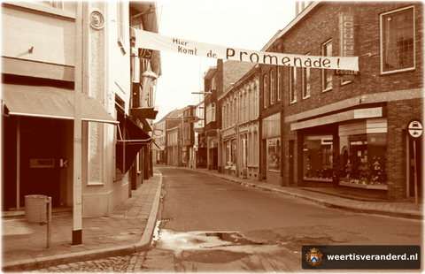 In 1972 was de Hoogstraat de eerste straat in de Weerter binnenstad die promenade werd. Rechts zien we al de gemoderniseerde zaak van de firma Coolen en links delicatessenzaak Kneepkens. Overigens heeft deze straat (gelukkig!) grotendeels z