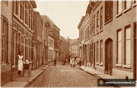 Een foto van de Hoogstraat met zijn statige panden. U kijkt richting Markt. Links bij het rijwiel begint het Prinsenstraatje. Let ook op de prachtige gaslantaarns en bestrating.