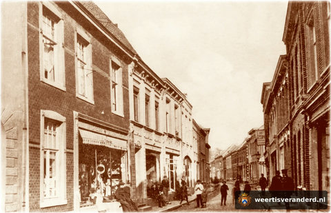 Veel bekijks voor de fotograaf in 1915. Het pand links op de foto werd later verbreed met een gedeelte van het pand Kneepkens, waar we nog net de stenen boog van de poort zien. Hierin kwam later de ijssalon van Janssen en het bijkantoor van