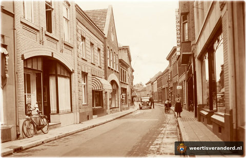 Op deze foto van 1930 zien we aan de linkerzijde achtereenvolgens de panden van Herenmode Vossen, bakkerij Söntjes, slager Jansen en de snoepwinkel van de familie Flapper. De eerste zaak rechts was de bazaar van Boonen, later Verspagen, nu