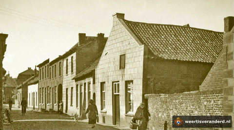 De Hogesteenweg gezien vanaf de Oelemarkt richting Beekstraat. Let op het vrouwtje op de voorgrond met körref en nuizik. In het witte pand vooraan woonde de familie Claessens (van Potten Ties), daarnaast Adriaens (van Baks). In het kleine h