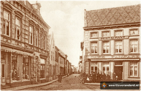 Het pand links op de hoek is al verbouwd. Voor het café Fanfare heeft zich iedereen verzameld voor de fotograaf.