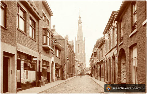 Doorkijk richting Markt met op de achtergrond de “Lange Jan”. Links kapper Gielis. Daarnaast de tabakswinkel van Tonia Adriaens. Rechts de doorgang naar Rijwielhandel Luys.