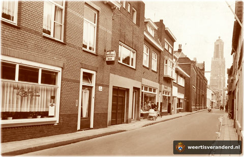 Café Limburgia is inmiddels verplaatst naar de overkant, daarnaast het huis van slijter “Koeke” Clerx, dan het kleuterhuis van Wiel Luys, de tabakswinkel van Adriaens (Baer en Tonia) en vervolgens de groentezaak van Frens Claessens (Pottent