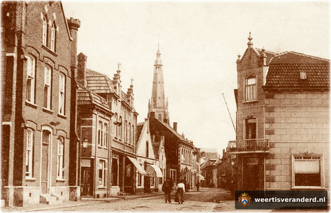 We kijken in de Langstraat, richting Markt. Geheel links staat nog de oude stadsschool, waar nu de Wilhelminasingel begint. Van de panden aan de linkerkant van de straat is alleen het witte puntgeveltje bewaard gebleven. Hier was bakkerij v