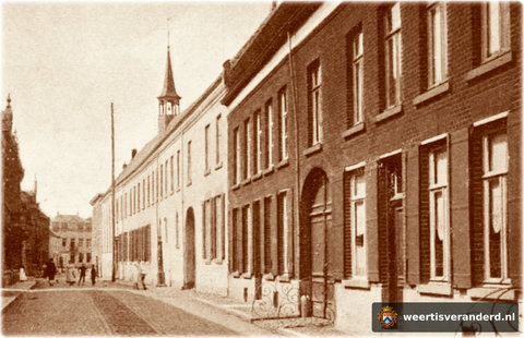 De poort in de bebouwing aan de rechterkant is er nog. Alleen is ze tegenwoordig fraai als voordeur geïntegreerd in modezaak Cramers-van Asten. Hier is ze nog mooi afgezet met een siersmeedwerk hekje. Let ook op de hoge telegraafmast.