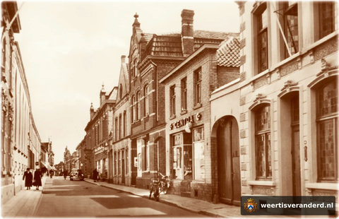 Uiterst rechts het pand van de toenmalige beschuitfabriek Poell. De poort is nu de doorgang naar het parkeerterrein erachter. Naast de Centra was het kruidenierswinkeltje van Nelleke Nouwen en daarnaast woonde van Kimmenade (Krake Frenske).