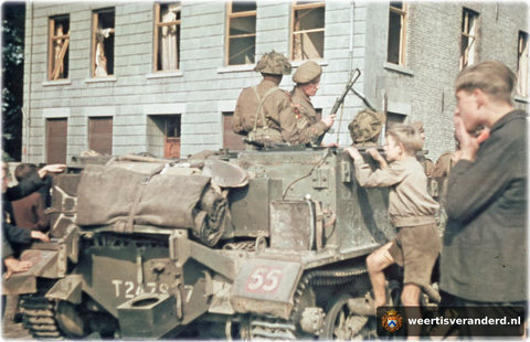 Kinderen kijken naar een carrier van het Suffolkregiment